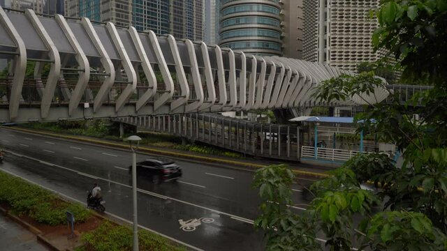rainy day jakarta city downtown famous pedestrian bridge traffic street top slow motion panorama 4k indonesia