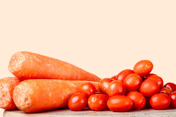 Cherry tomatoes on a wood next to three carrots.