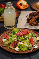 Caesar salad with grapefruit with grilled pork ribs, pickled vegetables and moonshine  on black wooden background