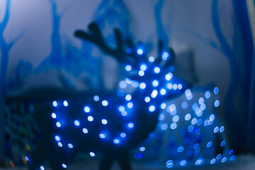 Blurred white deer made of wood with lanterns. Decoration for the new year. Bokeh effect