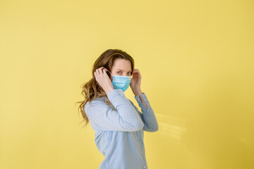 Beautiful caucasian brunette woman in protective medical mask on her face isolated standing on...