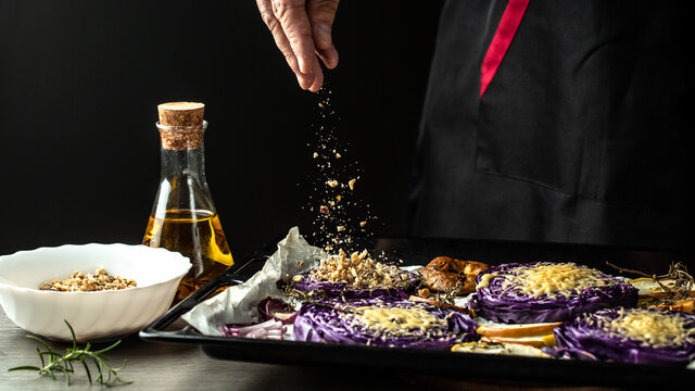 Chef Cook Preparing Vegetables Autumn Dish Of Red Cabbage Baked With Nuts, Quince And Apples, Flying Nuts Scattering In A Freeze Motion