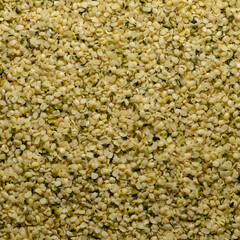 Hulled hemp seeds. Square shaped background and surface of raw and edible hempseeds.  Cannabis sativa, high in protein and a great source of iron. Macro, food photo, top view, from above. Backdrop.