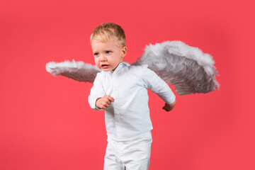 Funny Valentines day. Cupid angel child with wings is fun, isolated on red.