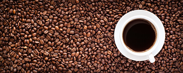 Roasted coffee bean background with a cup of hot espresso in the right side. Horizontal panorama banner with copy space