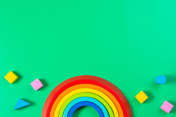 Baby kids toy background. Wooden stacking rainbow and colorful blocks on light green background....