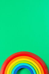 Wooden stacking toy rainbow on light green background