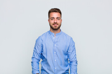 young man looking happy and smiling with hand on chin, wondering or asking a question, comparing...