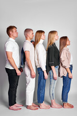 Obraz premium side view on group of youth standing in a row in descending order, beautiful people in casual wear posing, people diversity concept