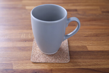 Gray cup standing on stand on wooden table at home close-up. Sufficient daily fluid intake concept