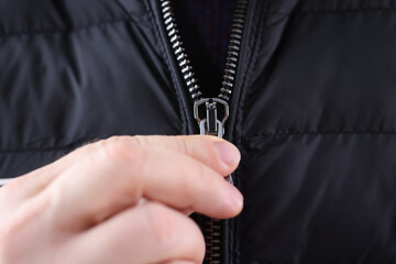 Male hand closing zipper on black jacket closeup. Custom tailoring concept