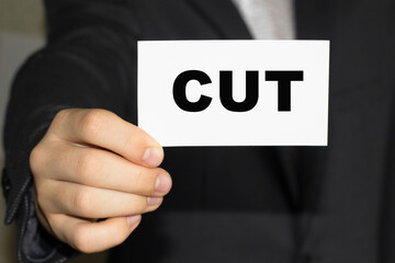 Card with text CUT on hand. You can use in business, marketing and other concepts. Messege of the day. CUT - business concept presented by businessman.