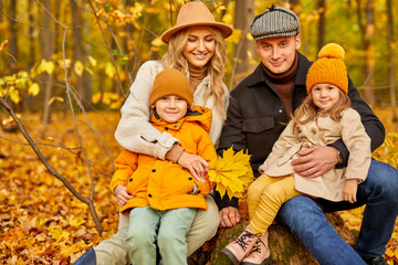 family with little kids in autumn park on sunny day, portrait of happy caucasian family while walking, aroung yellow trees