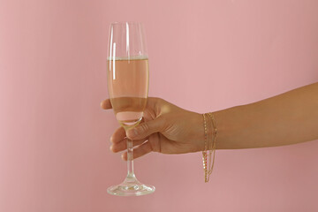 Female hand hold champagne glass on pink background