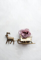 Christmas flatlay with vintage brass reindeer pulling a sleigh with a rose inside on white background 