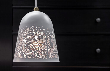 Openwork white metal lamp with floral ornaments.