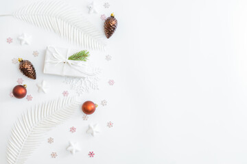 Flat lay frame with christmas baubles decoration, snowflakes and gift box on a white background