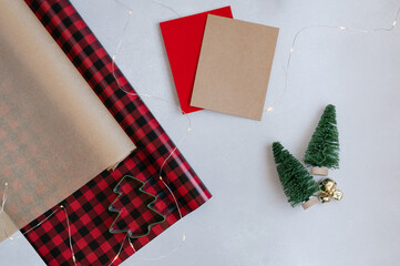 Fototapeta premium Christmas blank greeting card mock-up scene. Wrapping paper, Christmas tree, Christmas bells, twinkle lights. Blank space for copy, top view, flat lay festive view.