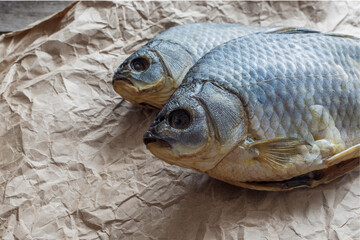 Salted Dry fish vobla on crumpled craft paper on wooden background