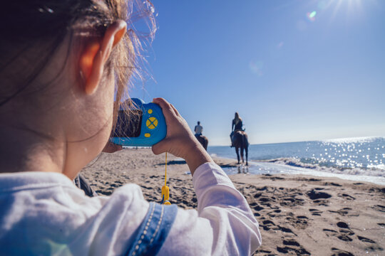 little baby girl while using a toy camera on the beach on a sunny day