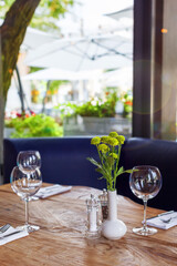 Laid table in a restaurant with a view of the summer terrace. Beautiful bokeh.