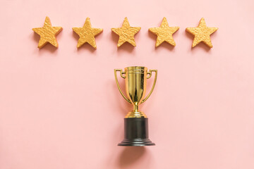 Simply flat lay design winner or champion gold trophy cup and 5 stars rating isolated on pink...