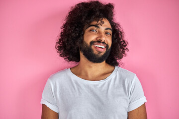 pleasant indian arabian male in shirt looking at camera, has friendly look, open-minded guy isolated over pink background