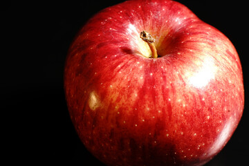 Red Apple on a black background. Half-light and a brightly lit Apple.
