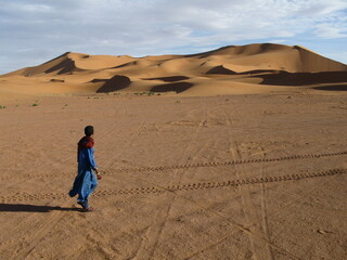 Young Berber man in front of sand dunes of Erg Chebbi, Morocco