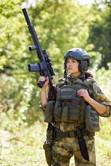 young caucasian military woman holds a gun in her hand in nature, she is going to hunt, hunting in forest is a hobby. game with weapons