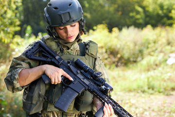 military woman is checking details of weapon before military training loading gun outdoors, sport shooting