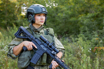 strong brave female army soldier with rifle machine gun standing in the forest, she is ready to...