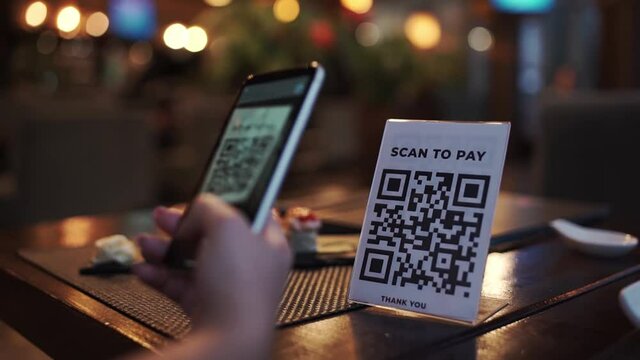 Scanning QR code with smart phone. The woman reads the bar code using the application on the smartphone in cafe