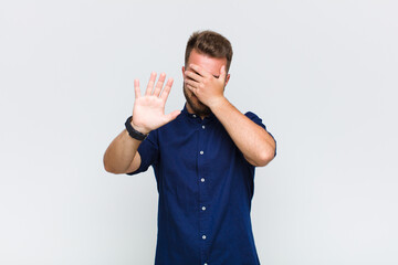 young man covering face with hand and putting other hand up front to stop camera, refusing photos...