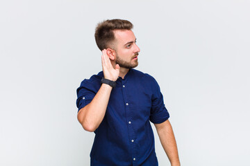 young man looking serious and curious, listening, trying to hear a secret conversation or gossip,...