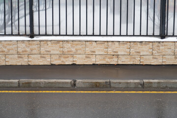 Sidewalk and curb wet from the rain and a metal fence, minimalism - obrazy, fototapety, plakaty