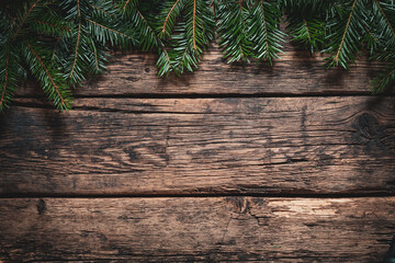 Christmas decoration background. Green fir branches on a rustic aged wooden wall. Space for copy.