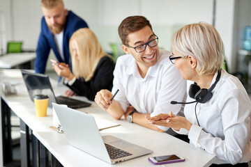 Obraz premium two colleagues sits talking at work, smiling. have fun, happy coopearation concept