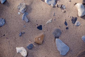 stones randomly studded in beach sand.