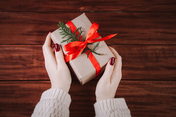 Hands hold beautiful gift box on wooden background. Christmas tradition.