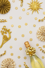 Festive background with gold decoration , gift boxes with bottle of sparkling wine, shiny golden serpentine confetti and paper christmas tree decorations, glittering snowflakes and deer