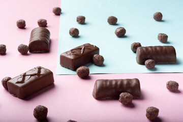 Chocolate candies with balloons on a colored background.