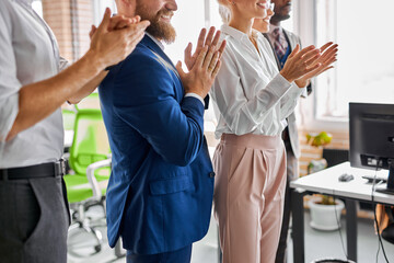 team of young diverse employees applauding, clapping hands, cheering mentor coach, in modern light...
