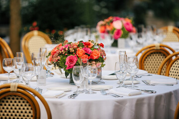 arrangement of pink and orange roses on dinner table with white tablecloth