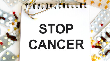 In the notebook the text of STOP CANCER, around a variety of tablets and stethoscope.