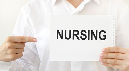 The doctor points to a notepad with the text NURSING.