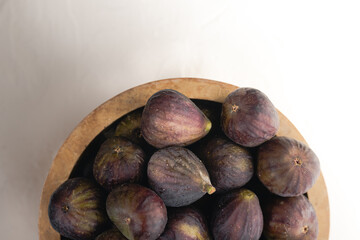A wooden bowl full of ripe figs