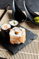 Various kinds of sushi served on black stone plates.