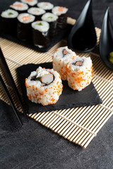 Various kinds of sushi served on black stone plates.