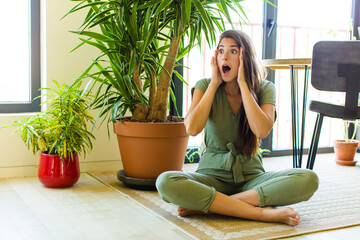 pretty woman feeling happy, excited and surprised, looking to the side with both hands on face